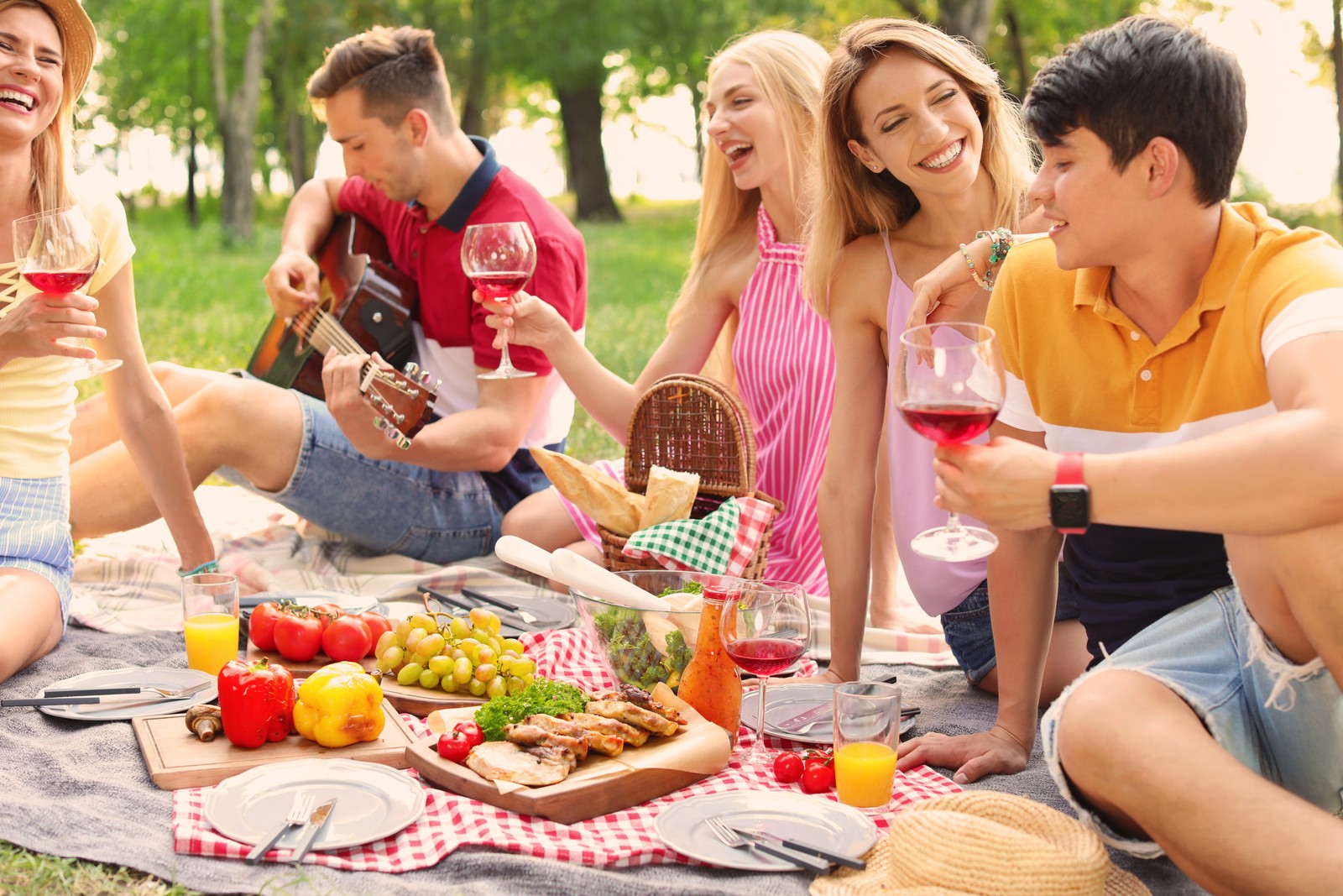 Photo of happy friends having picnic in park on sunny day