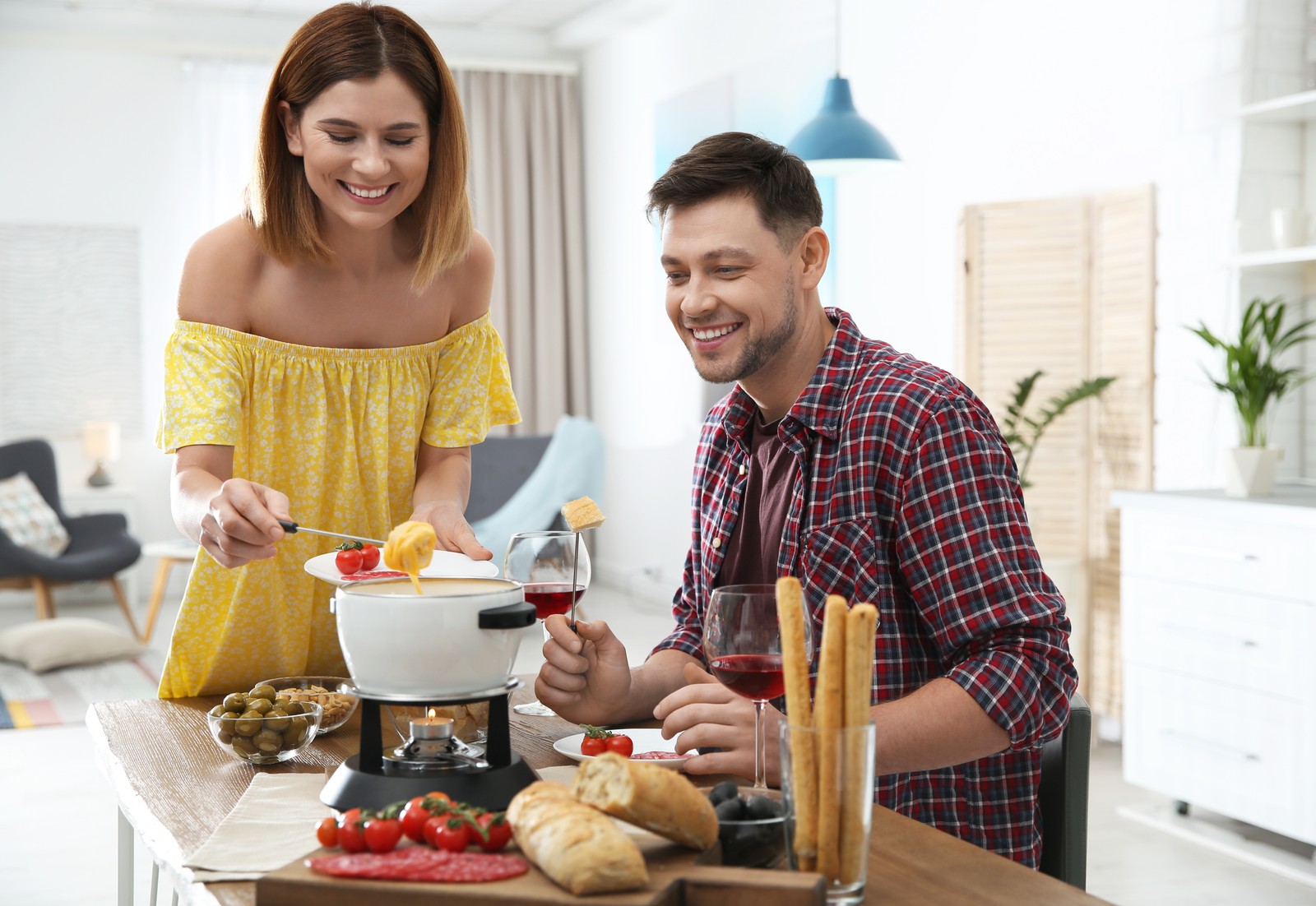 Photo of happy couple enjoying fondue dinner at home