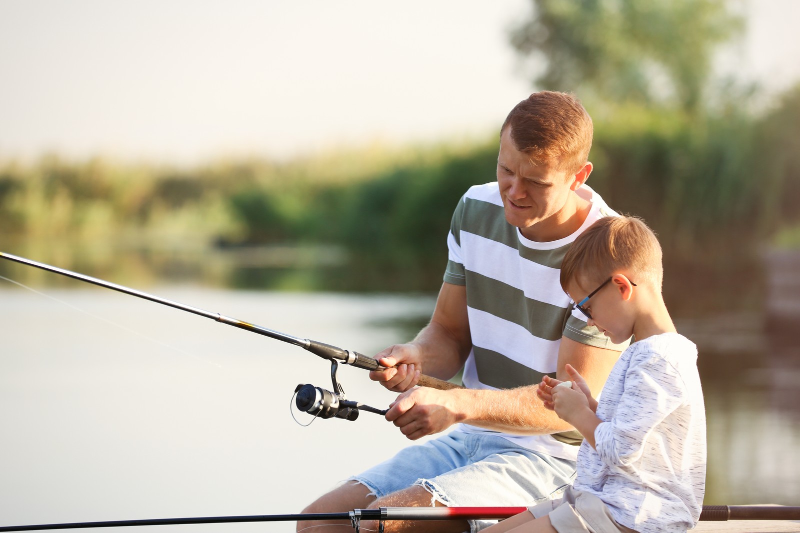 Photo of dad and son fishing together on sunny day