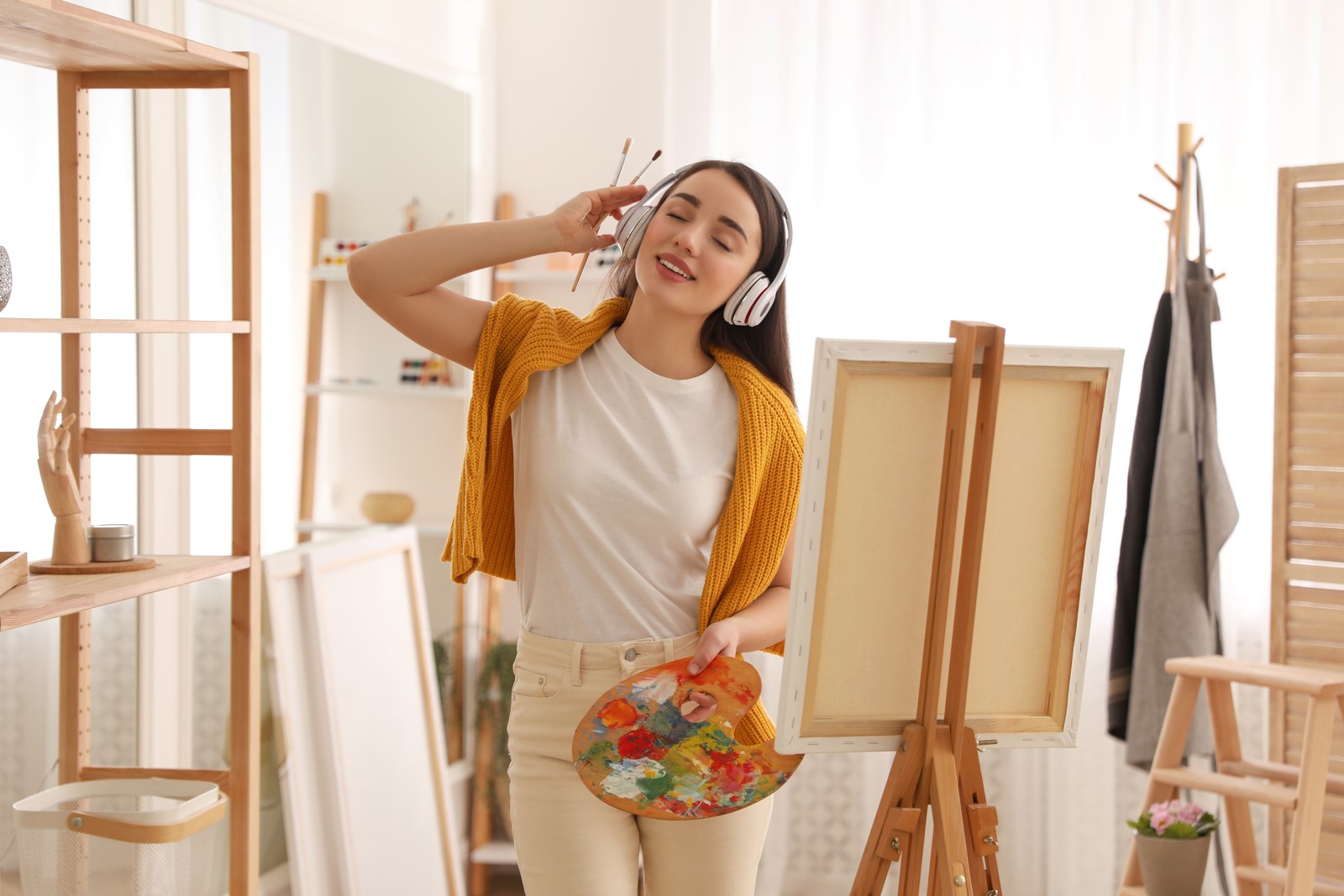 Photo of beautiful young woman listening to music while drawing at home