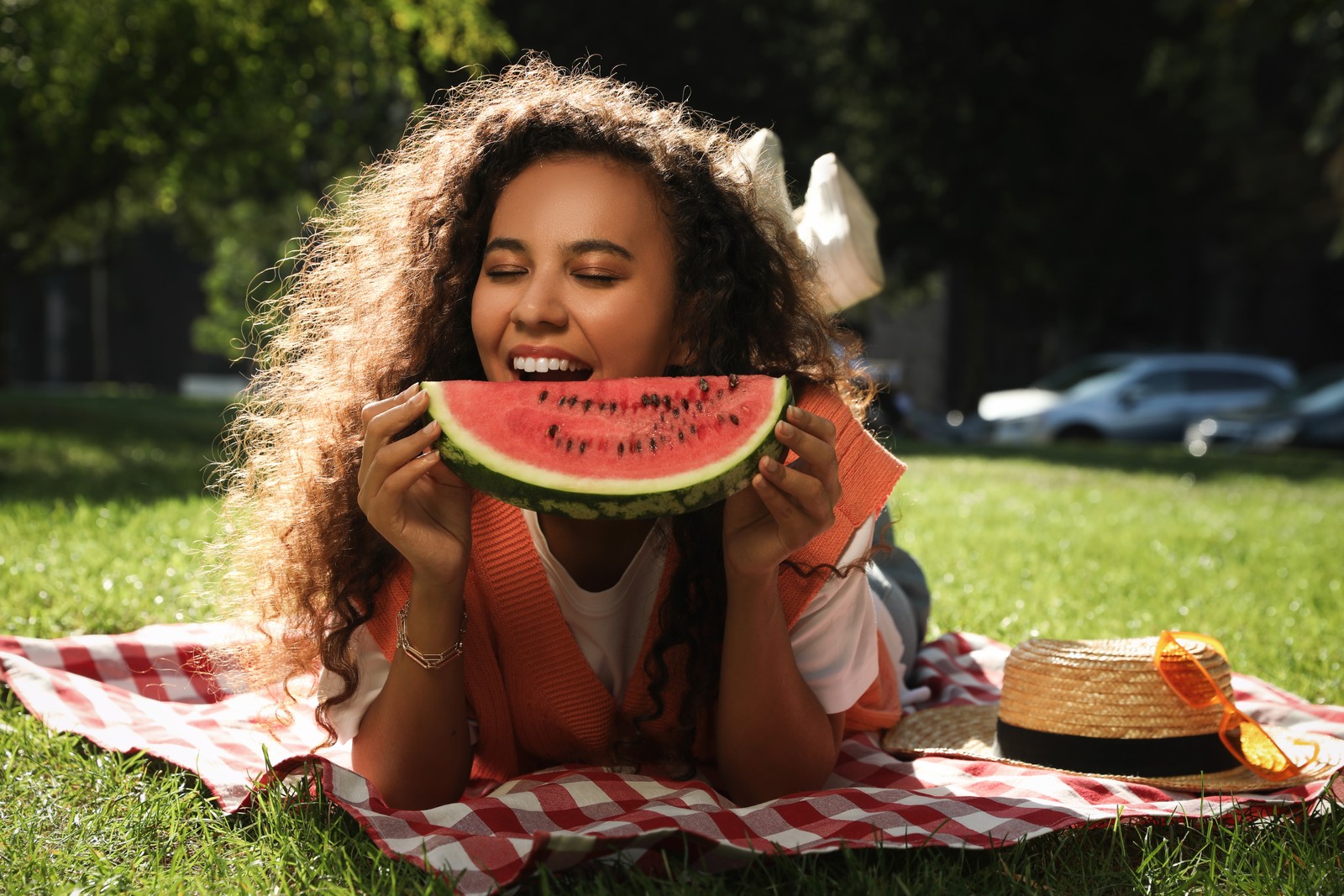 Photo of beautiful young African American woman with slice of watermelon in park