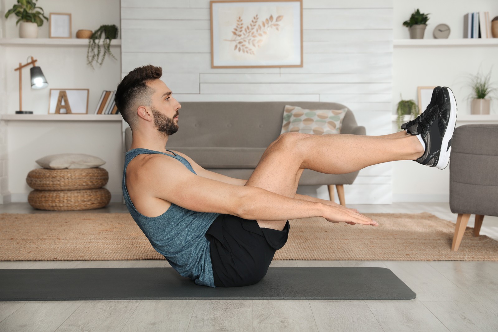 Photo of handsome man doing abs exercise on yoga mat at home