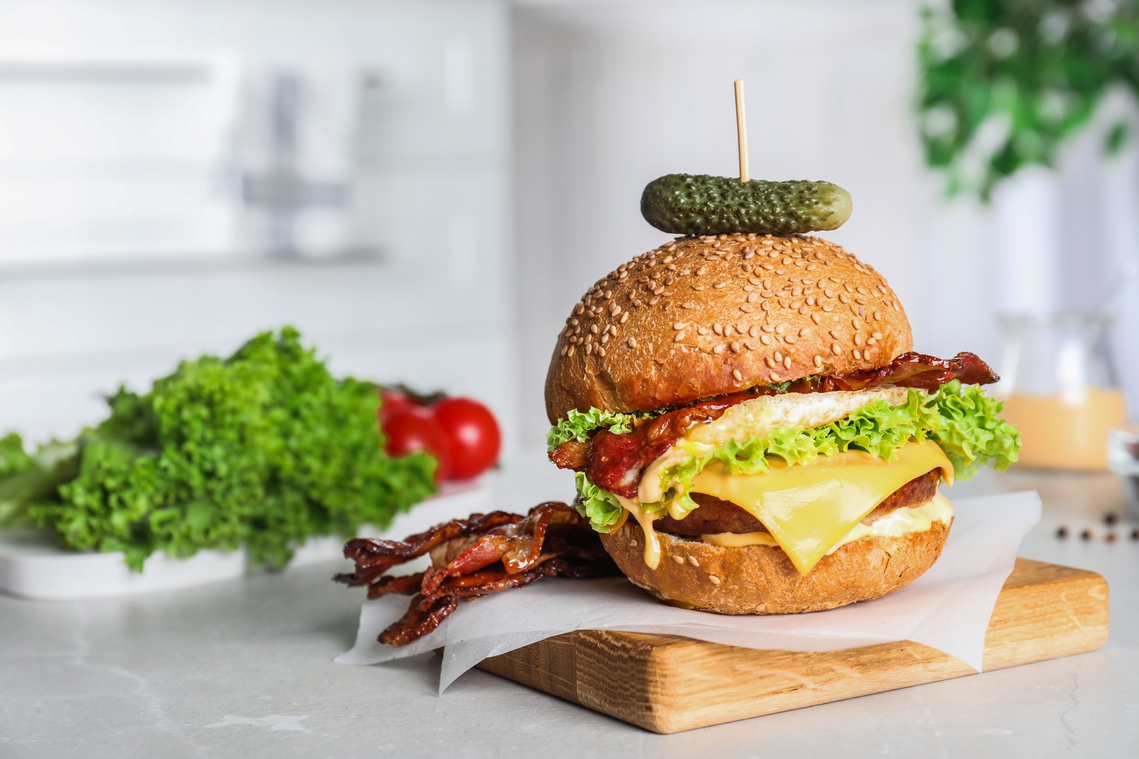 Photo of fresh juicy bacon burger on grey table. Space for text