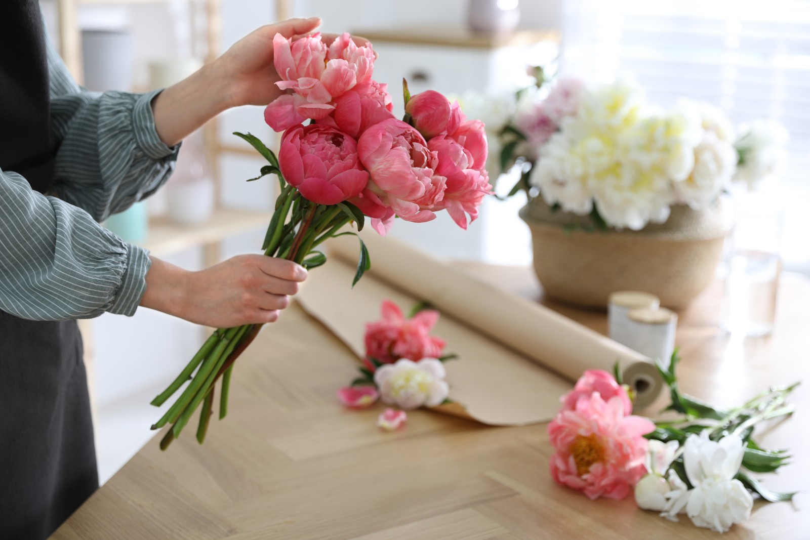 Photo of florist making beautiful peony bouquet at table, closeup