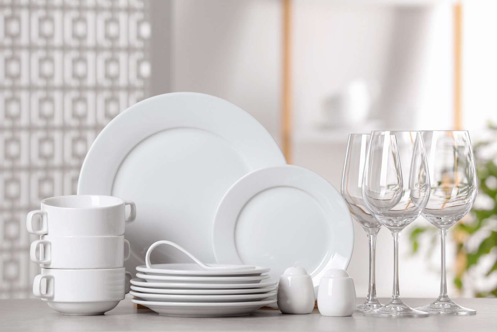 Photo of set of clean dishware and glasses on light grey table