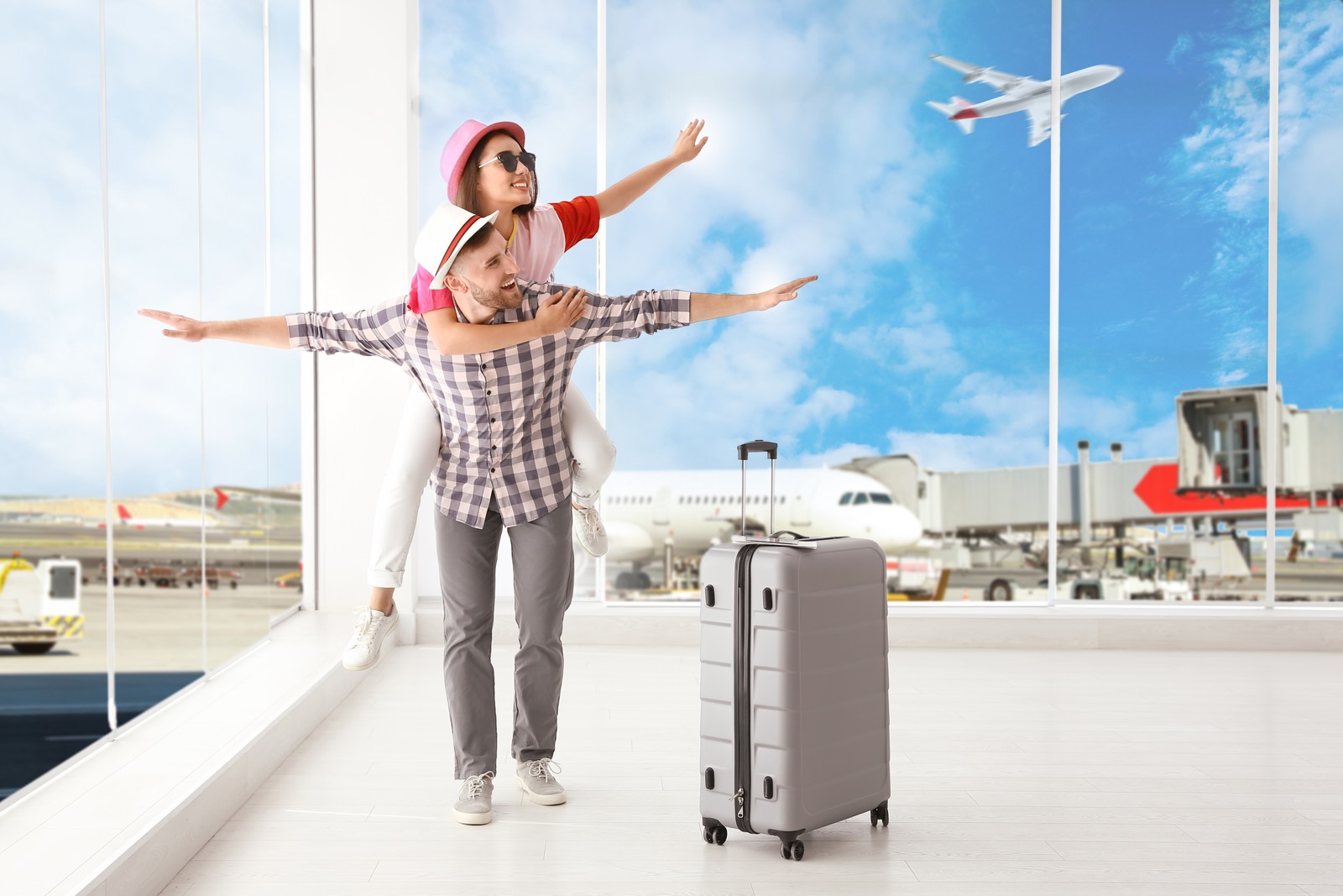 Photo of happy young couple with suitcase in airport