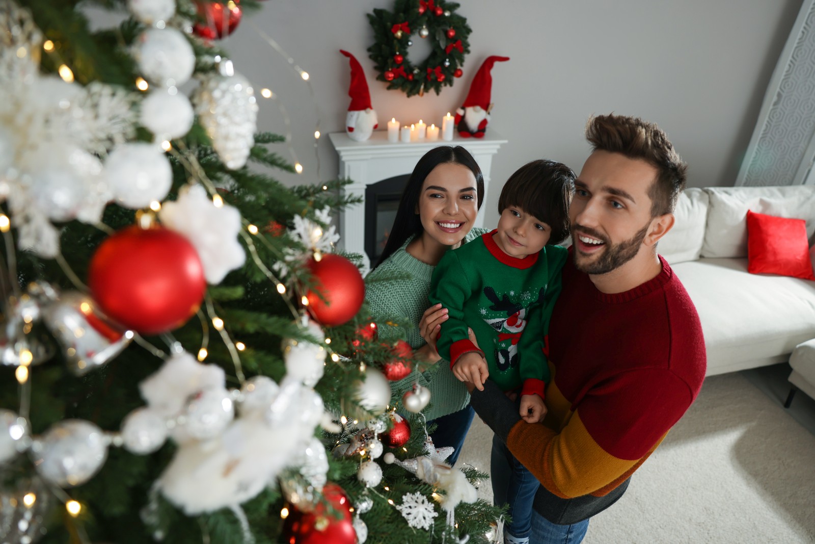 Photo of happy family decorating Christmas tree together at home, above view