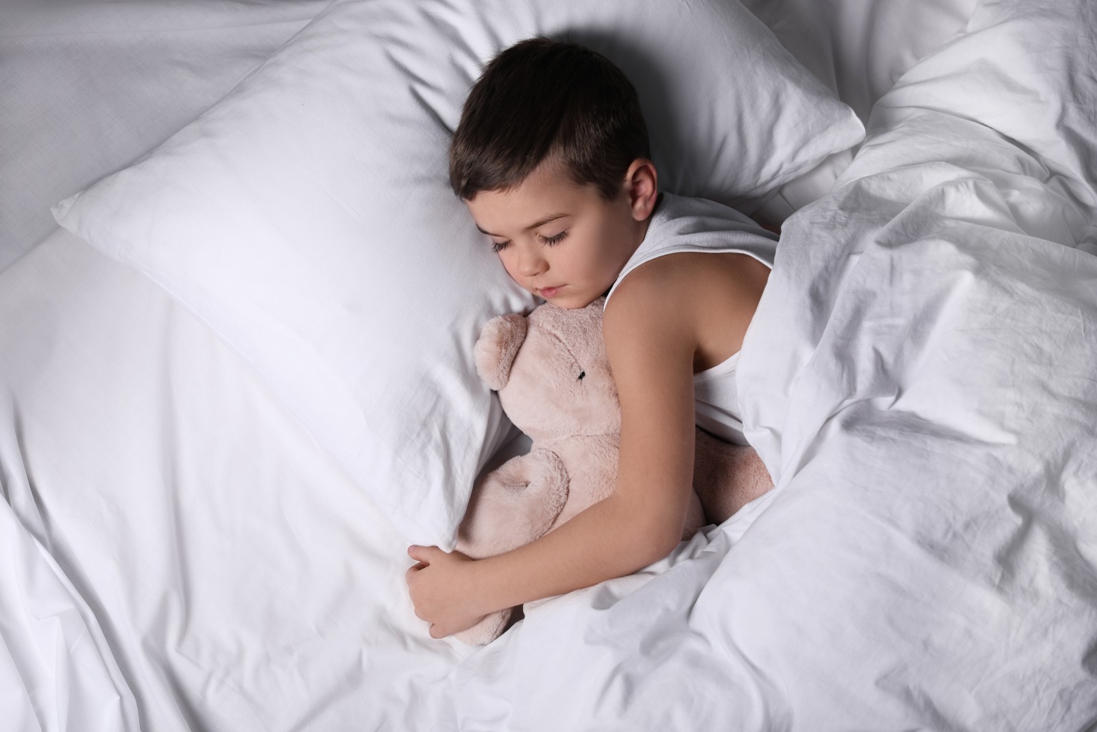 Photo of little boy sleeping with teddy bear at home. Bedtime