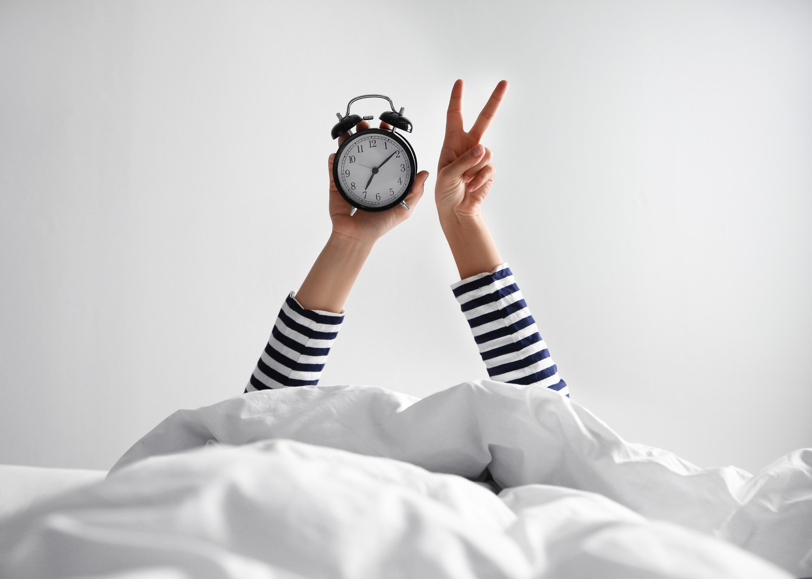 Photo of woman with alarm clock lying in bed, closeup. Morning time