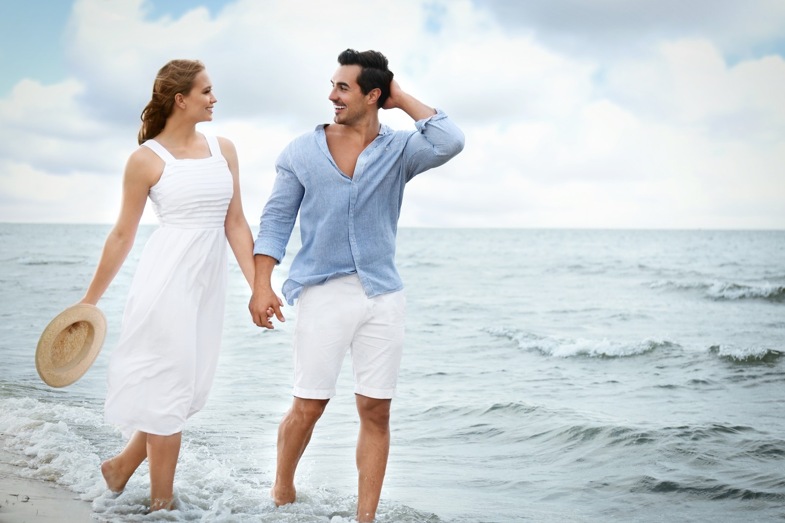 Photo of happy young couple walking on sea beach