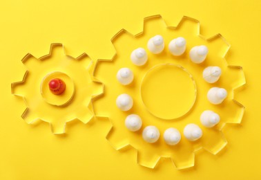 Photo of Employee selection process. Flat lay composition with cogwheels, red pawn as recruiter and white ones as applicants on yellow background