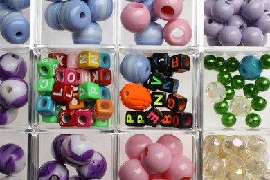 Plastic organizer with different beads as background, top view