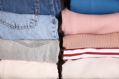 Photo of Different folded clothes as background, top view. Vertical storage of clothing