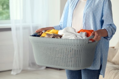 Photo of Woman with basket full of clean laundry indoors, closeup