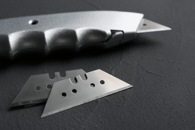 Utility knife and blades on black background, closeup