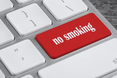 Red button with phrase No smoking on computer keyboard, closeup