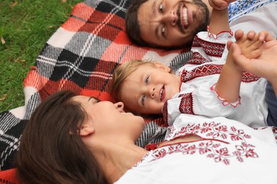 Photo of Happy family in national clothes lying on blanket outdoors
