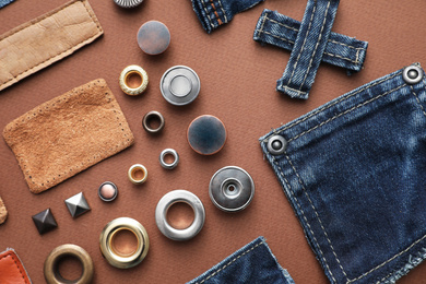 Photo of Flat lay composition with garment accessories and cutting details for jeans on brown background