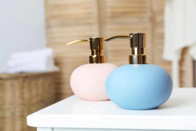 Stylish soap dispensers on table against blurred background. Space for text