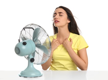Woman suffering from heat in front of fan on white background. Summer season