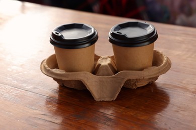 Photo of Paper coffee cups in carton holder on wooden table