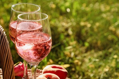 Photo of Glasses of delicious rose wine outside, closeup. Space for text