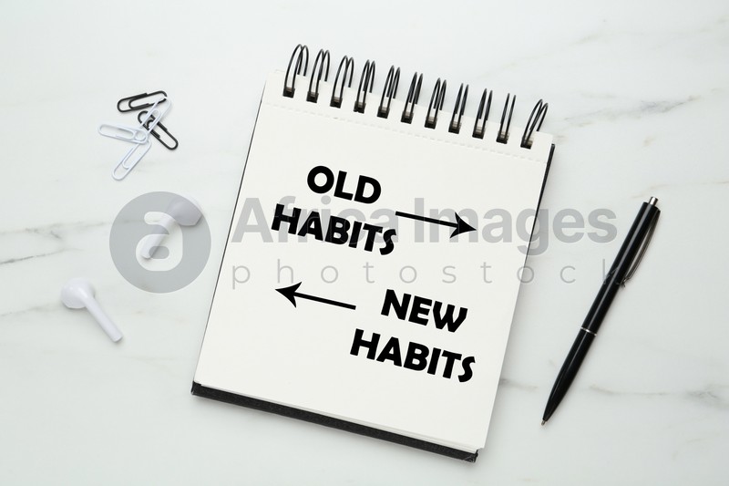 Notebook with two opposite directions to Old and New Habits on white marble background, flat lay