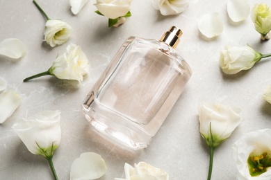 Composition of bottle with perfume and flowers on light grey marble background