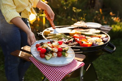 Photo of Woman cooking vegetables on barbecue grill outdoors, closeup