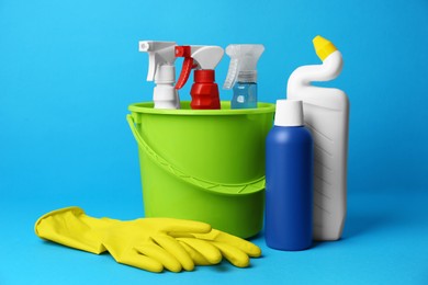 Green bucket, cleaning supplies and tools on light blue background
