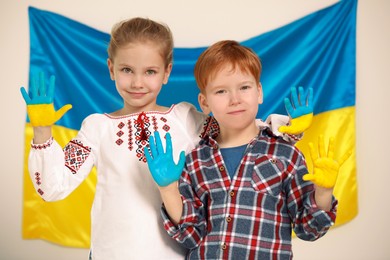 Photo of Little girl and boy with painted hands near Ukrainian flag. Love Ukraine concept