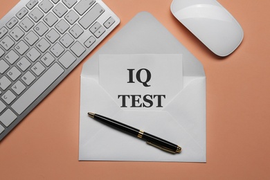 Note with text IQ Test in envelope, keyboard and mouse on coral background, flat lay