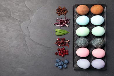 Photo of Naturally painted Easter eggs and space for text on black table, flat lay. Coffee beans, red cabbage, spinach, hibiscus, cranberries, blueberries used for coloring