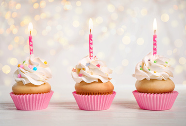 Birthday cupcakes with candles on white table. Bokeh effect