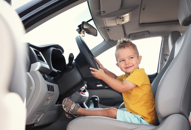 Photo of Little boy playing with steering wheel in car. Family trip