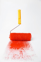 Photo of Roller brush and strokes of orange paint on white background