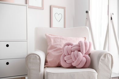 Photo of Pillows on light armchair indoors. Unusual cushion design