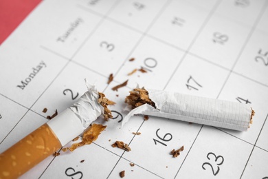 Calendar sheet with broken cigarette, closeup. Quitting smoking concept