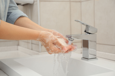 Woman washing hands with antiseptic soap in bathroom, closeup. Virus prevention
