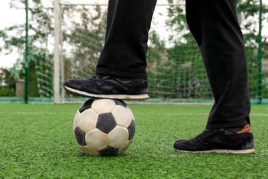 Photo of Man with soccer ball on green grass at stadium, closeup
