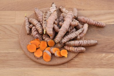 Photo of Board with fresh turmeric roots on wooden table, above view