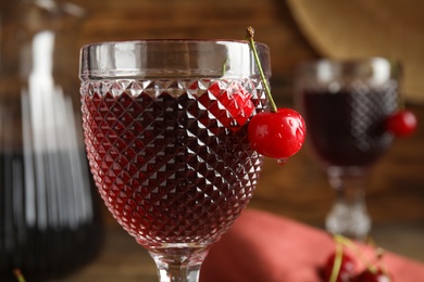 Delicious cherry wine with ripe juicy berries on blurred background, closeup