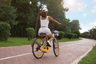 Young woman riding bicycle on lane outdoors, back view