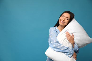 Beautiful Asian woman with pillow on blue background, space for text. Bedtime