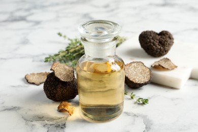 Photo of Fresh truffle and oil on white marble table, closeup