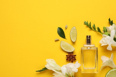 Flat lay composition with bottle of perfume and fresh citrus fruits on yellow background. Space for text