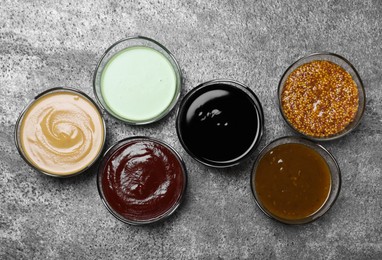 Many different sauces on grey table, flat lay