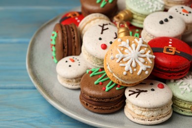 Photo of Beautifully decorated Christmas macarons on light blue wooden table, closeup