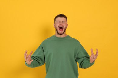 Aggressive young man shouting on orange background
