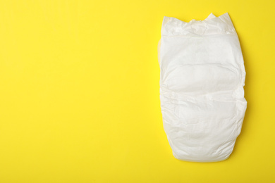 Baby diaper on yellow background, top view. Space for text